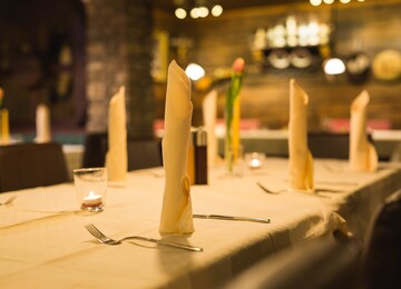 Gedeckter Tisch im Restaurant Obermayr mit gefalteten Servietten, Kerzen und einem gemütlichen Ambiente.