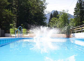Ein Sprung in den hoteleigenen Außenpool mit spritzendem Wasser.