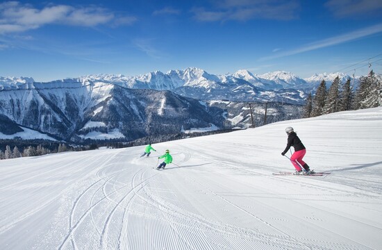 Eine Familie beim Schlittenfahren im Skiurlaub im Salzkammergut