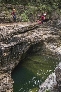 Ein Mann springt beim Canyoning in Salzburg von einer Klippe ins Wasser