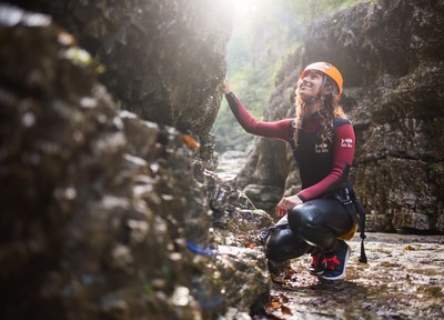 Eine Dame beim Canyoning - sitzend am Boden - in der Almbachklamm.