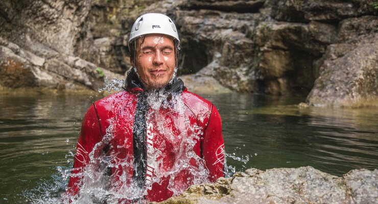 Ein Mann taucht beim Canyoning vom 3* Hotel Obermayr in Salzburg Umgebung aus dem Wasser