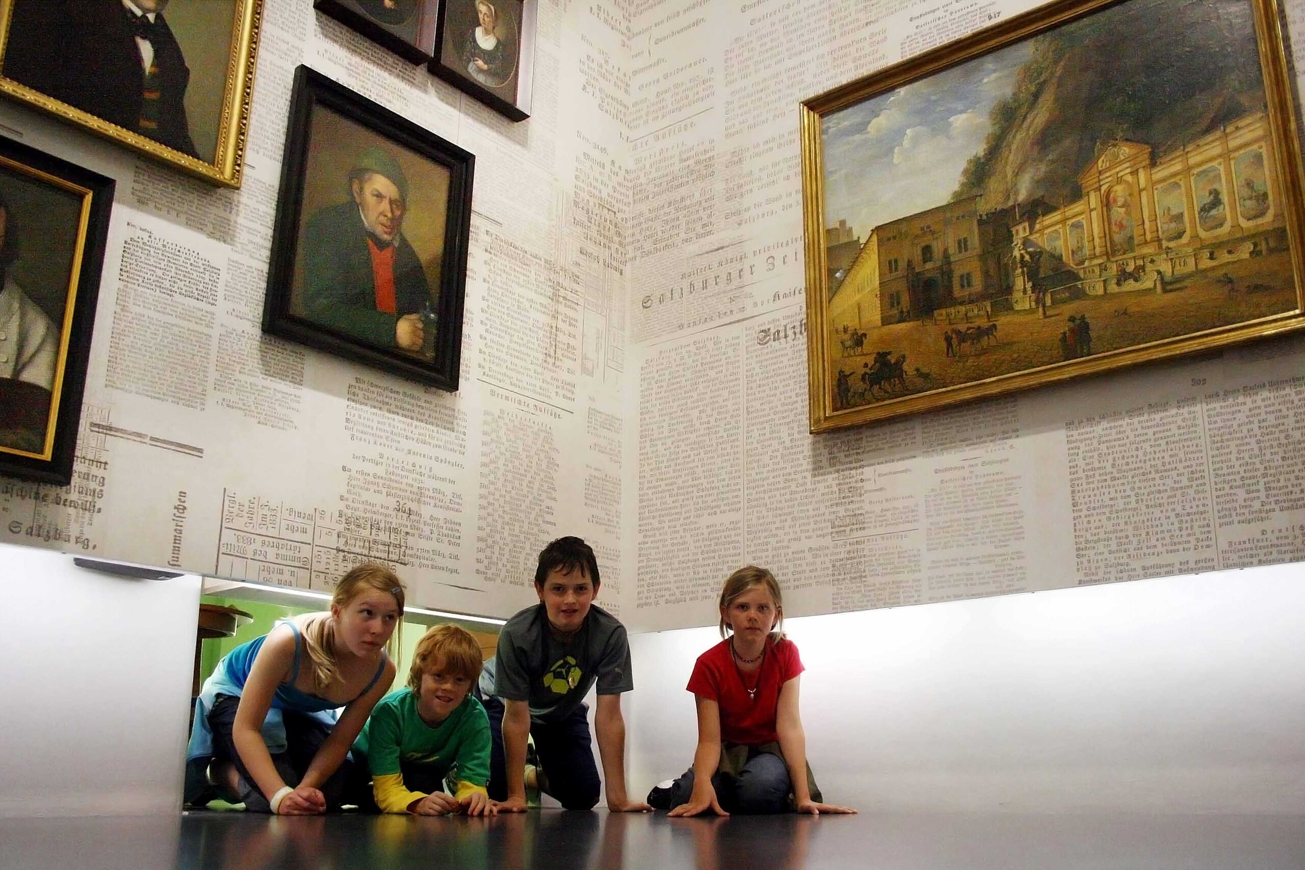 Kinder spielen in einem Raum mit Gemälden an der Wand.