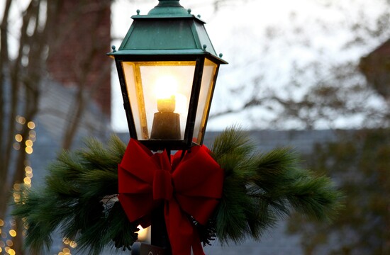 Eine Laterne mit Tannenzweigen und roter Schleife, weihnachtlich dekoriert.