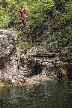 Ein Mann springt beim Canyoning in Salzburg von einer Klippe ins Wasser