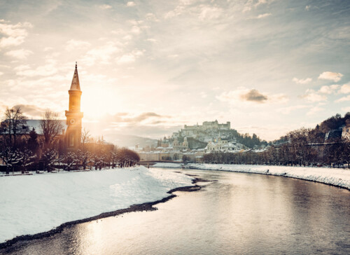 Salzburg im Winter mit Salzach, Kirchturm und Festung im Hintergrund.