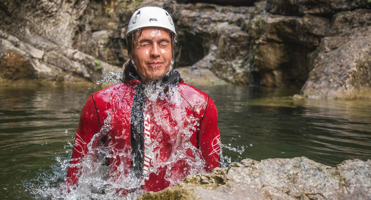 Ein Mann taucht beim Canyoning in Salzburg aus dem Wasser