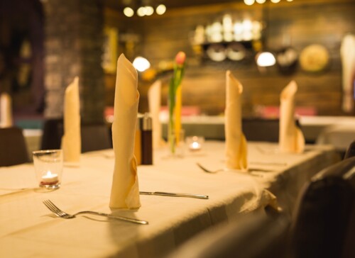 Gedeckter Tisch im Restaurant Obermayr mit gefalteten Servietten, Kerzen und einem gemütlichen Ambiente.